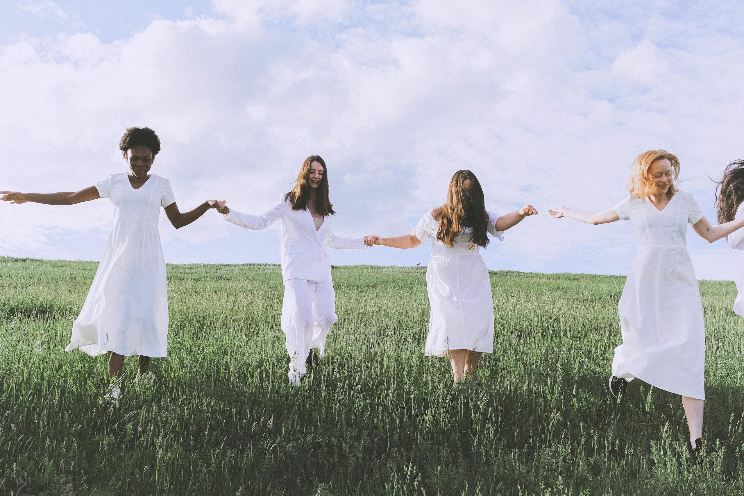 Women Walking on a Grass Field